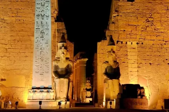Luxor Temple illuminated at night, showcasing its ancient Egyptian columns and architecture under a dark sky.